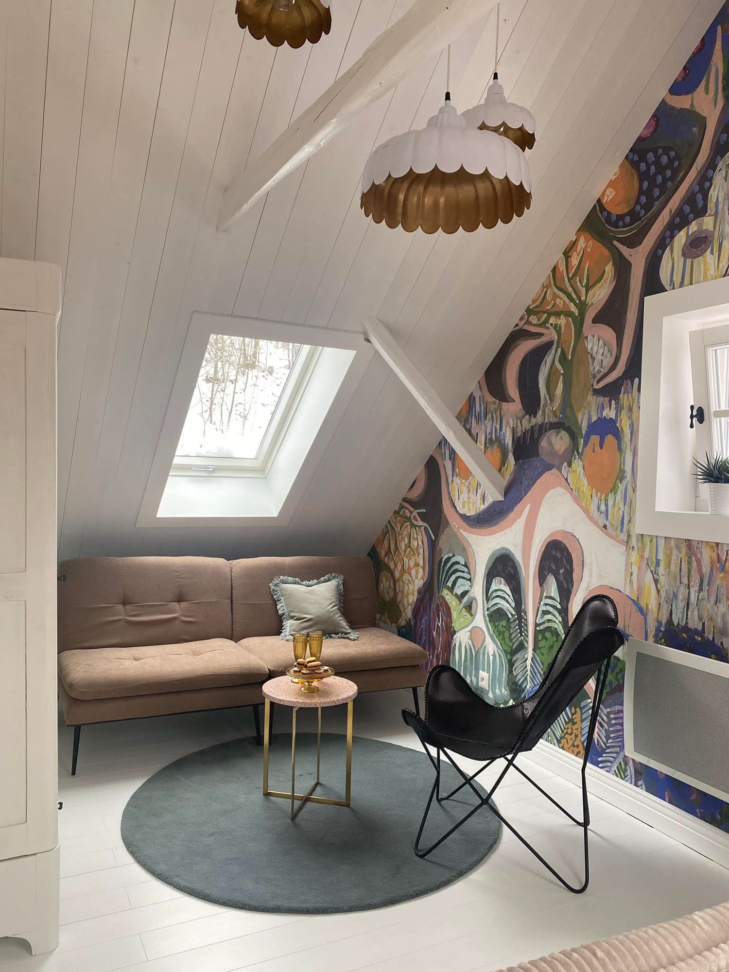 An attic bedroom in a mountain cabin featuring 'Purchawkowy Las' wallpaper by FREZO. The colorful, forest-inspired mural creates a cozy and artistic retreat in the Beskid mountains.